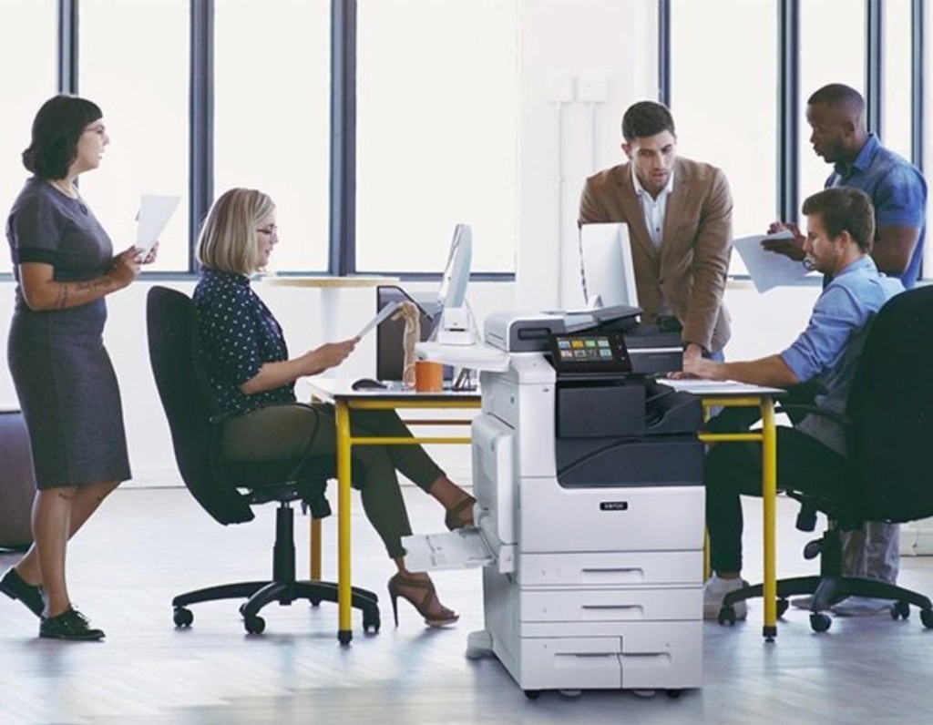 Office team working around a Xerox® VersaLink® B7125 multifunction printer in a modern workspace